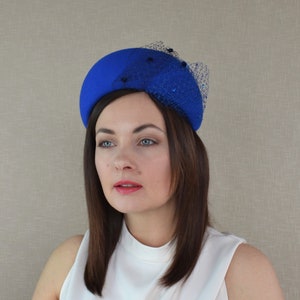 May include: A bright blue felt hat with a black net veil and blue embellishments.