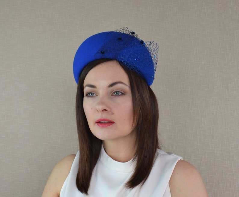 May include: A bright blue felt hat with a black net veil and blue embellishments.