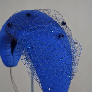 May include: A blue felt hat with a black net veil and blue sequins.