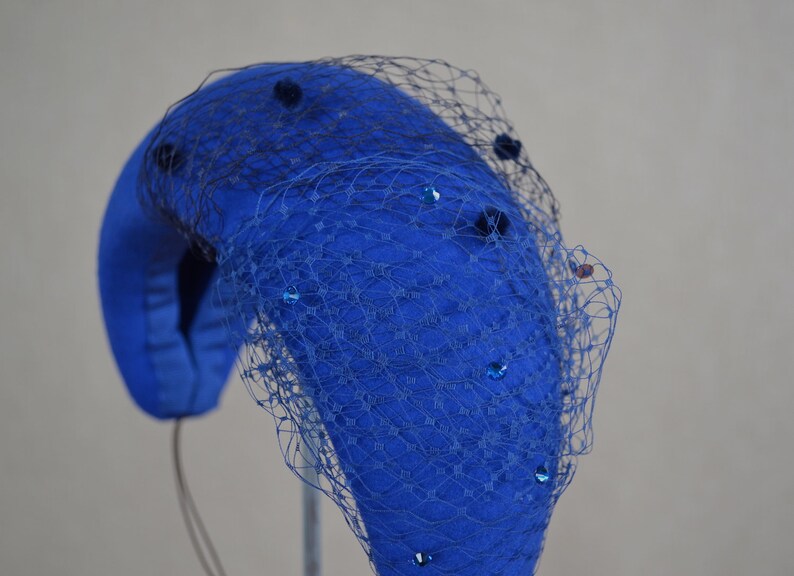 May include: A blue felt hat with a black net veil and blue sequins.