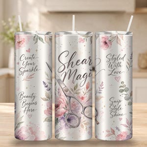 Puede incluir: Un vaso cilíndrico con pajita que presenta un diseño floral en tonos rosa y morado. El texto dice Create Your Sparkle, Beauty Begins Here, Shear Magic, Styled With Love y Snip Style Shine, junto a un gráfico de unas tijeras de peluquería.