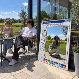 Pode incluir: Um espelho retangular de chão projetado para se assemelhar à interface do software Microsoft Paint. A moldura apresenta uma borda branca com uma barra de ferramentas à esquerda, uma barra de menu no topo rotulada untitled-Paint e uma paleta de cores.