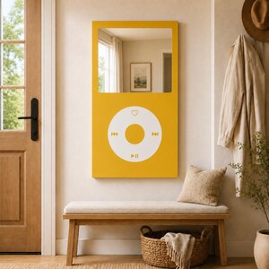 May include: A rectangular wall mirror featuring a mustard yellow frame designed to resemble a vintage digital music player. The upper portion is a reflective glass surface, while the lower section displays a white circular control interface.