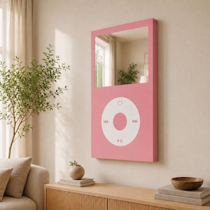May include: A rectangular wall mirror with a pink frame designed to resemble a digital music player. The upper portion is a reflective glass mirror, while the lower section features a white circular control interface with a heart icon.