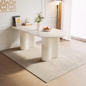 Mesa de comedor familiar, tablero de piedra sinterizada color crema con base de pedestal estriada.