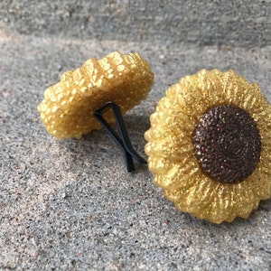 May include: Two gold glitter sunflower car air fresheners. The sunflowers have a brown glitter center.