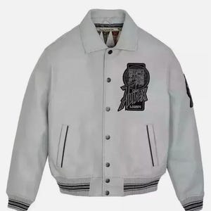 May include: A light gray leather jacket featuring a pointed collar, snap-button front closure, and ribbed cuffs and hem with black stripes. A black patch on the chest displays the text Avirex USA inside a circular graphic design.