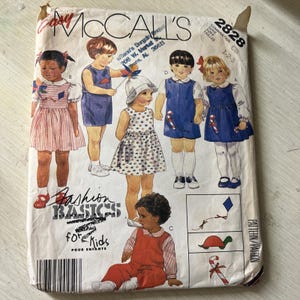 May include: A McCall's 2828 sewing pattern envelope for children's clothing featuring illustrations of five children wearing various outfits including dresses, jumpers, and overalls. The white paper envelope displays the text Fashion Basics for Kids.