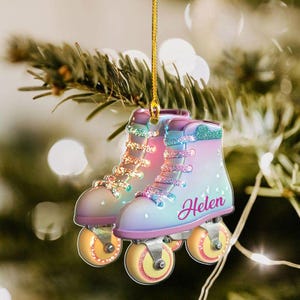 May include: A hanging ornament shaped like a pair of roller skates with a pastel gradient of pink, purple, and blue. The skates feature glittery laces and wheels, with the name Helen printed in cursive script on the side of the boot.