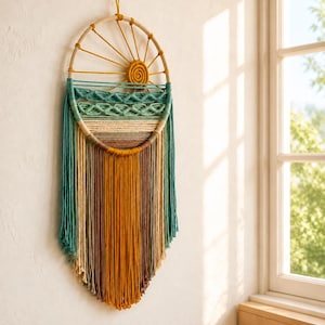 Op de afbeelding: Een ronde macramé wandhanger met een houten ringframe. Het ontwerp bevat een mosterdgele spiraalvormige zon, groenblauwe golfachtige knopen en horizontale banden van beige en bruin garen, afgewerkt met lange, veelkleurige franjes.