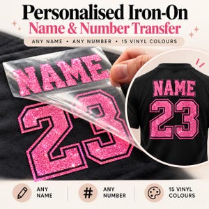 Op de afbeelding: Een gepersonaliseerde opstrijkbare naam- en nummeroverdracht met roze glittervinyl. De transfer toont het woord NAME en het nummer 23, waarbij een doorzichtig schutvel wordt losgetrokken van een zwarte stoffen ondergrond.