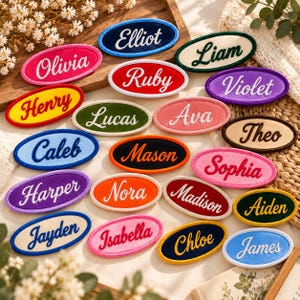 May include: A collection of oval-shaped embroidered patches featuring various names in cursive script, including Elliot, Liam, Olivia, Ruby, Violet, Henry, Lucas, Ava, Theo, Caleb, Mason, Sophia, Harper, Nora, Madison, Aiden, Jayden, Isabella, Chloe, and James.