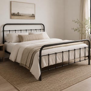May include: A black metal bed frame with a rounded headboard and footboard featuring vertical spindles and decorative spherical joints. The bed is dressed in a white duvet, two white pillows, and a long, rectangular beige lumbar pillow.