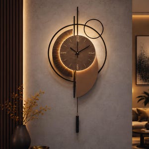 Puede incluir: Un reloj de pared con esfera circular y números dorados en las 12, 3, 6 y 9. El reloj está enmarcado por anillos y arcos geométricos de metal negro, realzado con retroiluminación cálida integrada y un péndulo negro fino colgando.