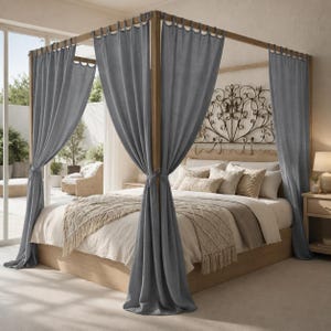 May include: A four-poster bed frame made of light-toned wood, featuring long, slate-blue fabric curtains hanging from the top rails. The bed is dressed in neutral-colored bedding with a textured throw blanket and decorative pillows.