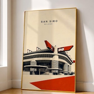 May include: A rectangular wall art print in a thin gold frame featuring a graphic illustration of the San Siro stadium in Milan. The artwork displays the stadium structure in black, white, and red against a cream background with the text SAN SIRO MILANO.