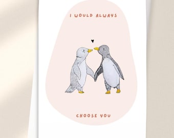 May include: A white greeting card featuring a light pink organic shape in the centre. Inside the shape are two illustrated penguins holding flippers with a small black heart above them. The text reads I WOULD ALWAYS CHOOSE YOU in orange.