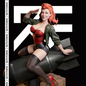 May include: A collectible figurine of a person with red hair, wearing a red corset, black shorts, and an olive green jacket, saluting while sitting on a dark green bomb. The figure wears black stockings and red high heels, positioned above wooden crates.