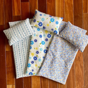 May include: Four blue and white patterned pillowcases, two with a floral design, one with a striped design, and one with a small floral design. The pillowcases are arranged on a wooden surface.