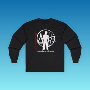 May include: A black long-sleeve shirt featuring a white graphic of a person standing inside a circle with an atom symbol and a compass. The word DEVO is printed in red vertically, and the text duty now for the future is printed in white.