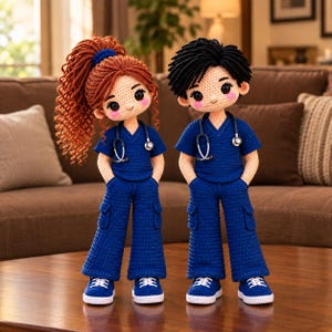 May include: Two crochet dolls dressed in matching navy blue medical scrubs with cargo pants and white sneakers. Each doll features a stethoscope around the neck, rosy cheeks, and dark eyes. One doll has long curly auburn hair, while the other has short black hair.