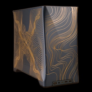 Puede incluir: Una torre de computadora gris oscuro con un patrón de líneas topográficas de color dorado en los paneles frontal y lateral. El panel lateral incluye una sección de ventilación perforada y la base frontal presenta una fila de puertos.