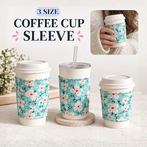 Op de afbeelding: Drie koffiebekerhoezen in drie maten, met een lichtblauwe achtergrond en een wit en roze kersenbloesempatroon. De tekst 3 SIZE COFFEE CUP SLEEVE staat bovenaan. Elke hoes is om een witte beker gewikkeld.