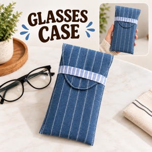 Puede incluir: Un estuche para gafas rectangular hecho de tela azul con finas rayas verticales blancas. El estuche presenta una banda horizontal de tela a rayas azul claro y blanco sobre la solapa frontal. El texto GLASSES CASE es visible arriba.