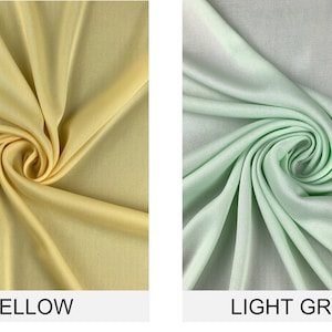 May include: Two fabric swatches, one yellow and one light green, are shown in a close-up view. The fabric is smooth and has a slight sheen.
