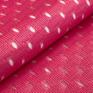 Puede incluir: Tela rosa con un patr&oacute;n de malla blanca. La tela es texturizada y tiene un brillo sutil.