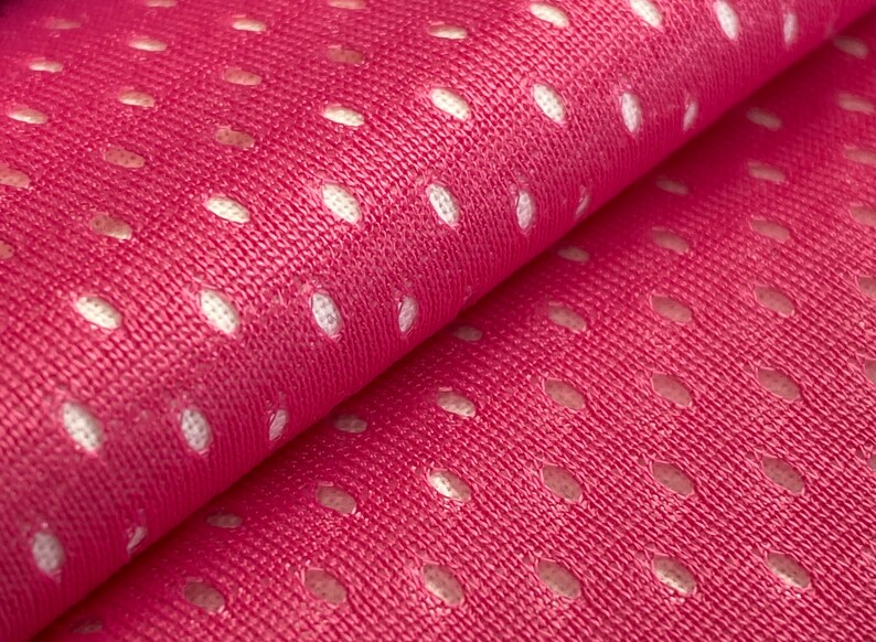 Puede incluir: Tela rosa con un patr&oacute;n de malla blanca. La tela es texturizada y tiene un brillo sutil.