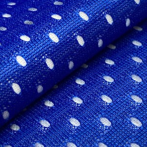 Puede incluir: Primer plano de una tela azul con agujeros ovalados blancos. La tela es texturizada y tiene un brillo sutil.