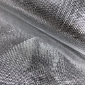 May include: Close-up of a silver-colored mesh fabric with a fine, even weave. The fabric is folded in half, creating a diagonal line across the image.