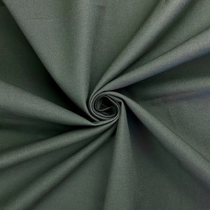 May include: Close-up of a dark green fabric with a smooth texture. The fabric is folded and draped, creating a soft, flowing look.