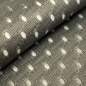 Puede incluir: Primer plano de una tela gris con un patr&oacute;n de lunares blancos. La tela es texturizada y tiene un brillo sutil.