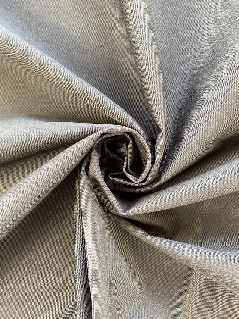 May include: Close-up of a dark gray fabric with a smooth, slightly textured surface. The fabric is folded and twisted, creating a swirling pattern.