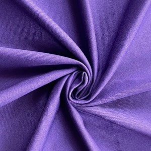 May include: Purple stretch fabric with a smooth, slightly textured surface. The fabric is folded and twisted, showing its drape and flexibility.