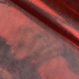 May include: Close-up of a red mesh fabric with a subtle sheen. The fabric has a fine, even weave and a slightly textured surface.