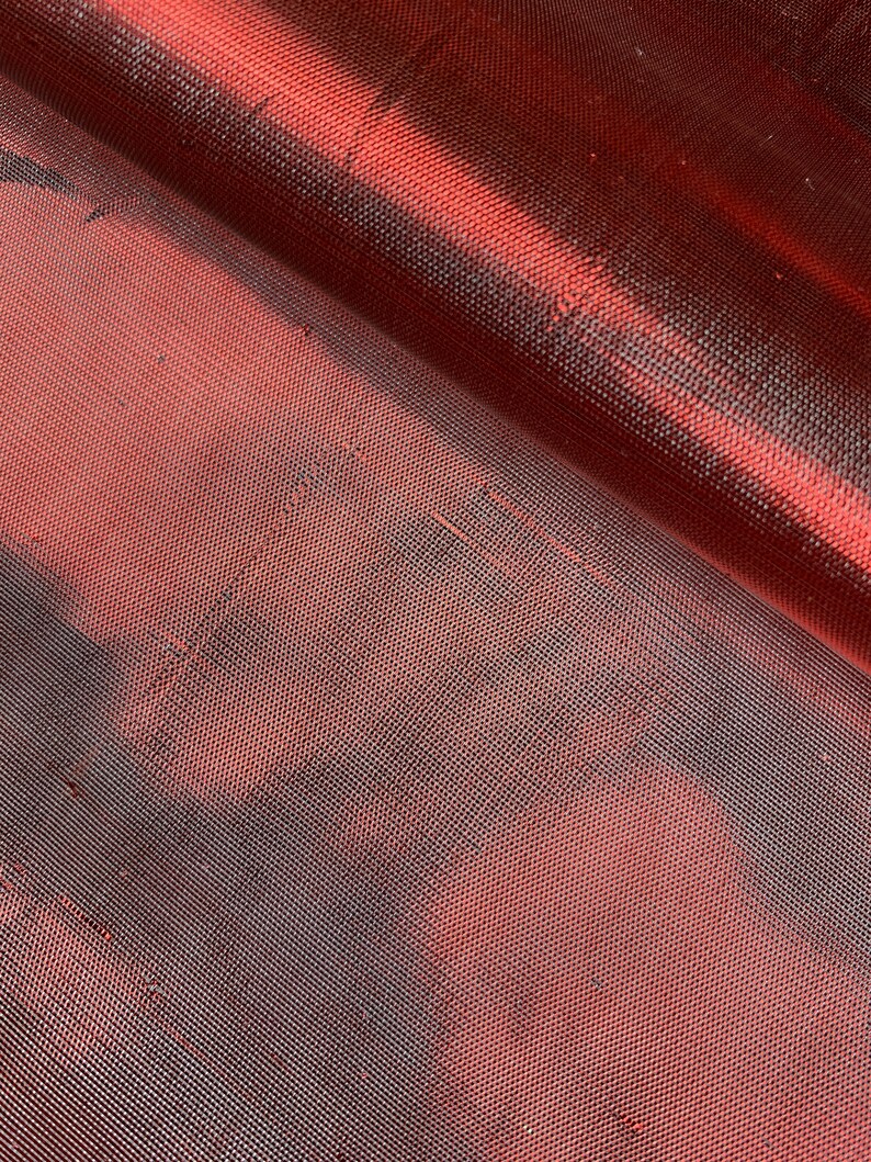 May include: Close-up of a red mesh fabric with a subtle sheen. The fabric has a fine, even weave and a slightly textured surface.