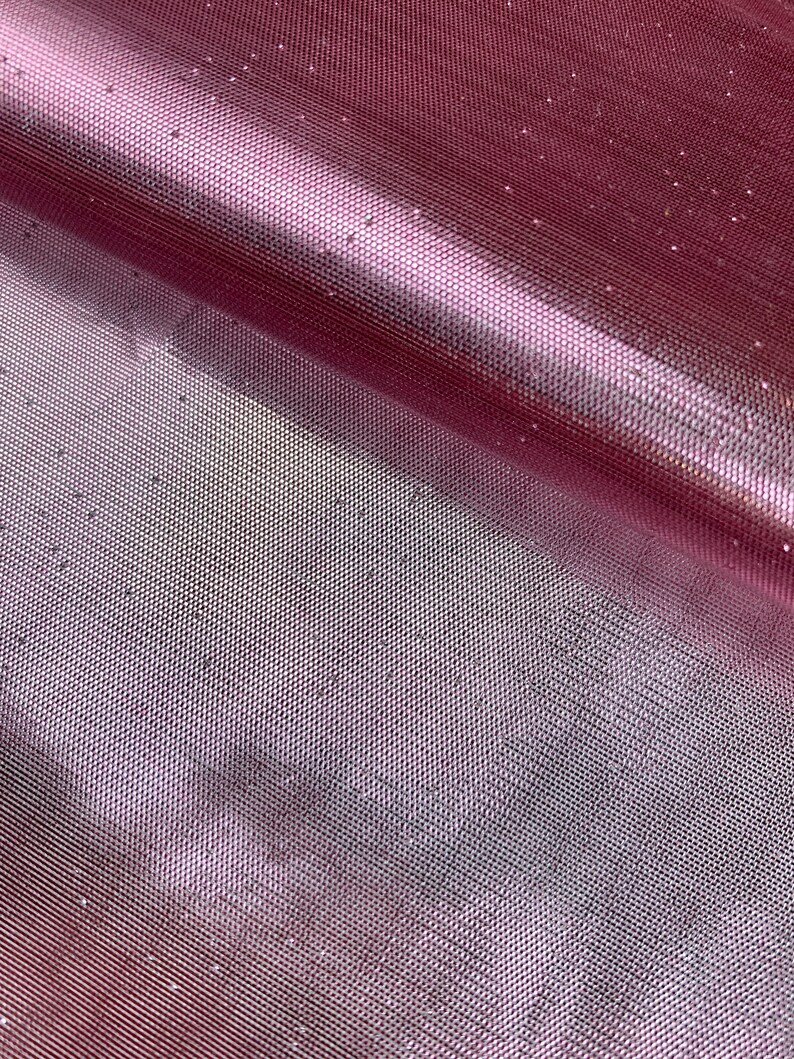 May include: Close-up of a pink glittery mesh fabric. The fabric has a fine, even weave and is shimmering with tiny silver glitter particles.