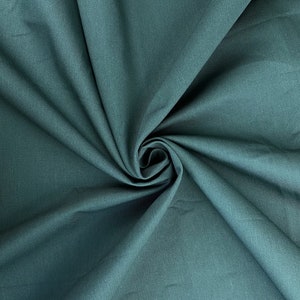 May include: A close-up of a teal fabric with a smooth texture. The fabric is folded and draped, creating a soft, flowing look.
