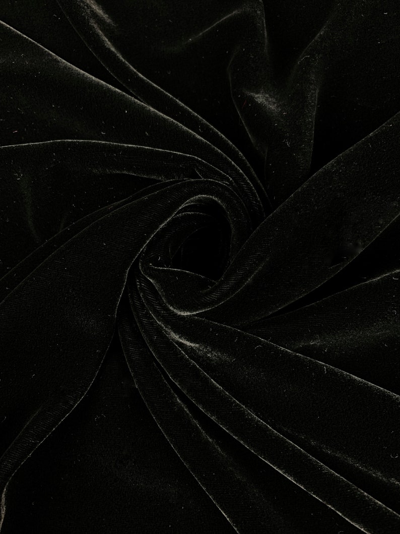 May include: Black velvet fabric with a soft, smooth texture. The fabric is draped and folded, creating a swirling pattern.