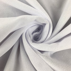 May include: White velvet fabric with a soft, plush texture. The fabric is folded and draped, showcasing its smooth surface and subtle sheen.
