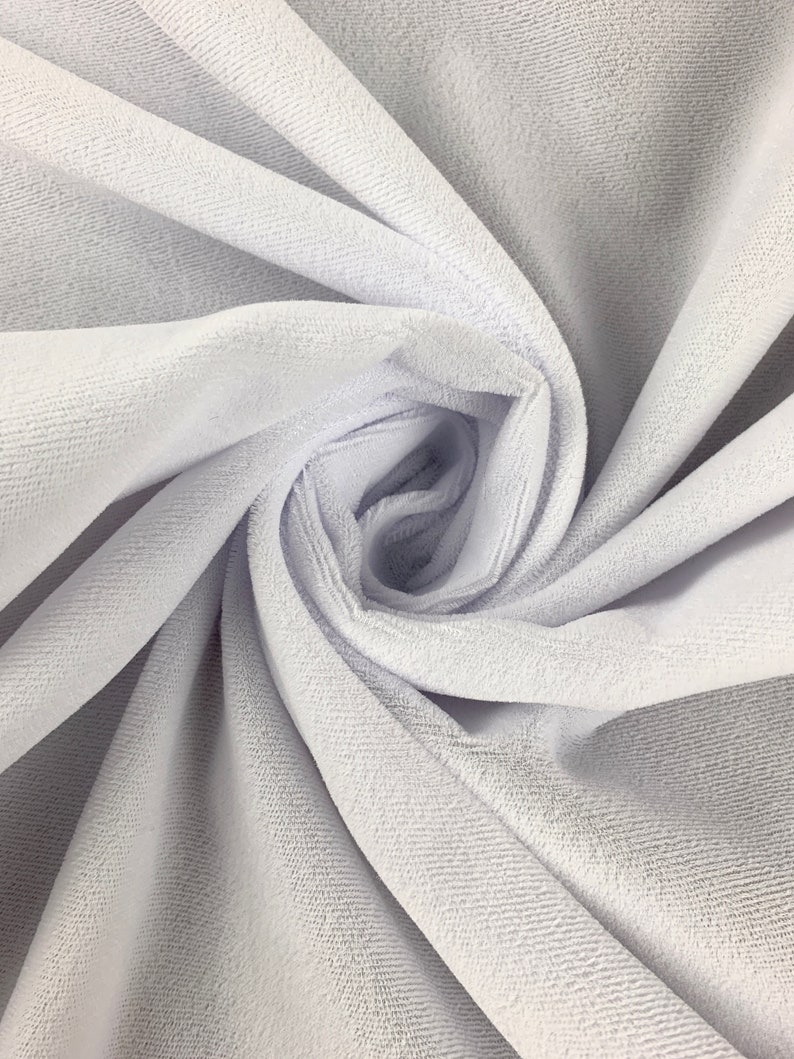 May include: White velvet fabric with a soft, plush texture. The fabric is folded and draped, showcasing its smooth surface and subtle sheen.