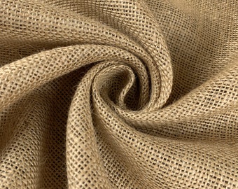 May include: Close-up of a natural brown burlap fabric with a woven texture. The fabric is folded and draped, showing its soft, pliable nature.