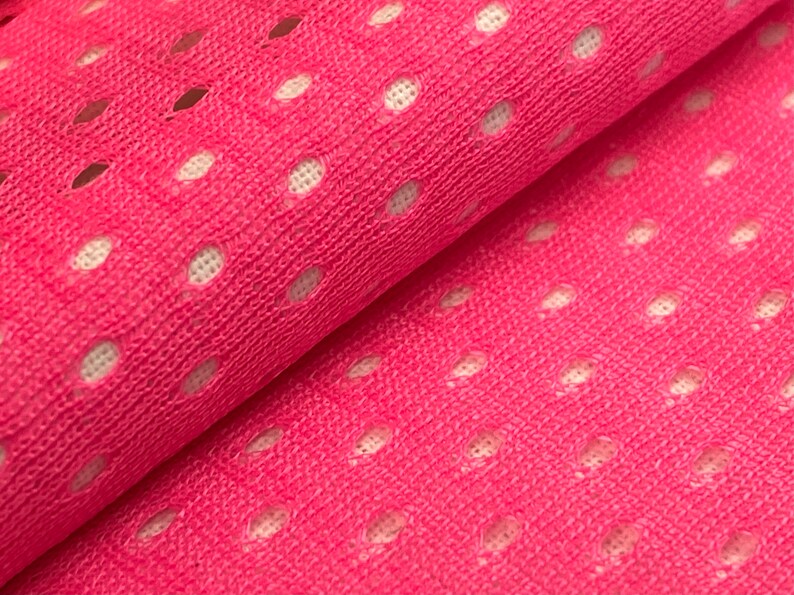 Puede incluir: Tela rosa con un patr&oacute;n de malla blanca. La tela est&aacute; doblada por la mitad, mostrando la textura del material.