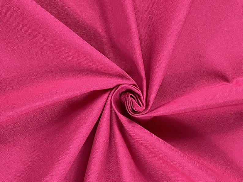 May include: Close-up of a vibrant pink fabric with a smooth, slightly textured surface. The fabric is folded and twisted, creating a dynamic and abstract pattern.