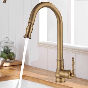 Può includere: Un rubinetto da cucina ad arco alto con finitura in ottone antico spazzolato. Il rubinetto è dotato di una doccetta estraibile con un flusso d'acqua costante e una leva laterale singola per controllare il flusso e la temperatura dell'acqua.