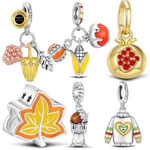 Può includere: Una collezione di sei ciondoli in metallo color argento e oro con motivi autunnali, tra cui una pigna, una ghianda, una foglia, una zucca, una pannocchia, un melograno con cristalli rossi, uno scoiattolo e un maglione con un cuore.