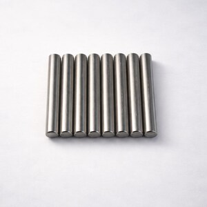 Könnte beinhalten: Ein Set aus acht identischen, zylindrischen Metallstäben, die parallel nebeneinander angeordnet sind. Jeder Stab hat eine glatte, silberfarbene Oberfläche mit flachen, kreisförmigen Enden, was ein einheitliches und strukturiertes Erscheinungsbild ergibt.